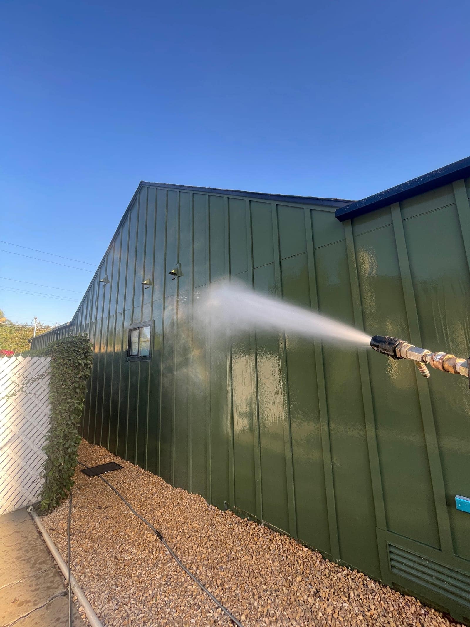 Soft washing the exterior wall of a Santa Barbara home, grime rinsing away